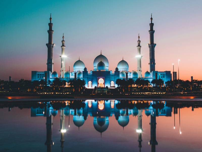 Sheikh Zayed Grand Mosque reflected in a pool at dusk