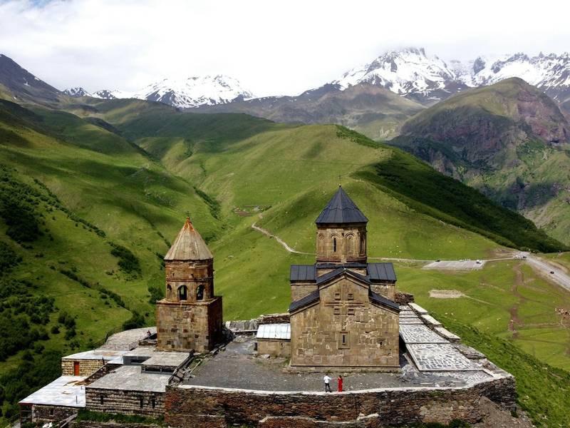 Gergeti Trinity Church on a green hill below the Caucasus mountains