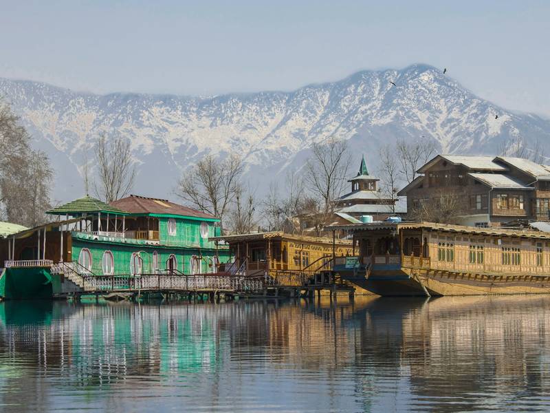 Houseboats moored on a lake below snow-covered mountains in Kashmir