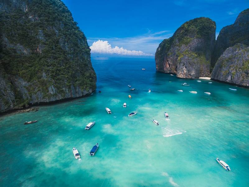 Boats on turquoise water between limestone cliffs at Maya Bay, Thailand